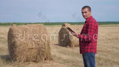 智慧<strong>农业</strong>理念.. 一名农民工人在<strong>数字</strong>平板电脑上的田野里研究干草堆。 慢速视频